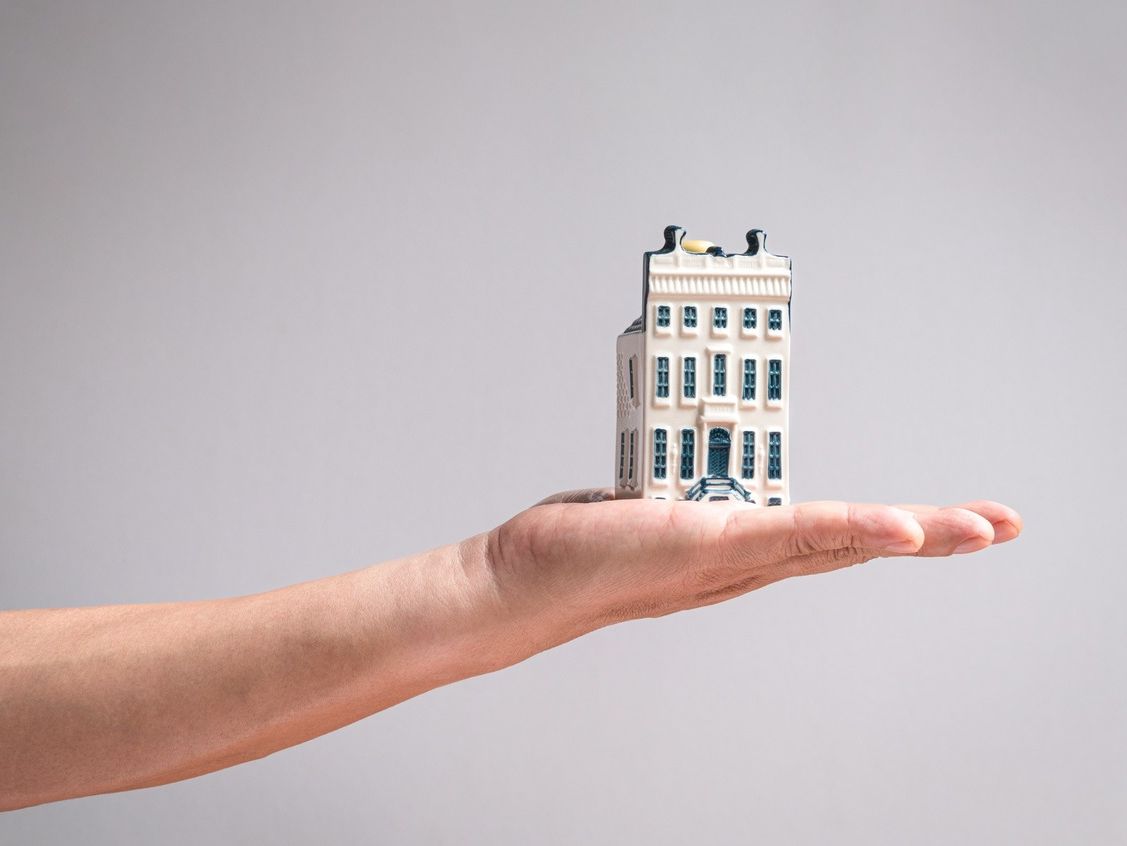 mano con edificio miniatura fondo aislado